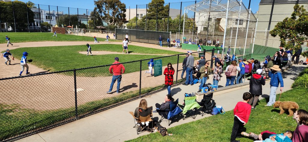Families relax in sunshine on a lovely April Sunday afternoon. Fourth-graders from St. Cecilia run the bases as St. Gabriel defends.